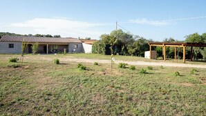 A rural property with a stone house, a wooden pergola, and a grassy field.