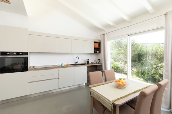 Una cocina moderna con armarios blancos, una estufa negra y un comedor con mesa y sillas.