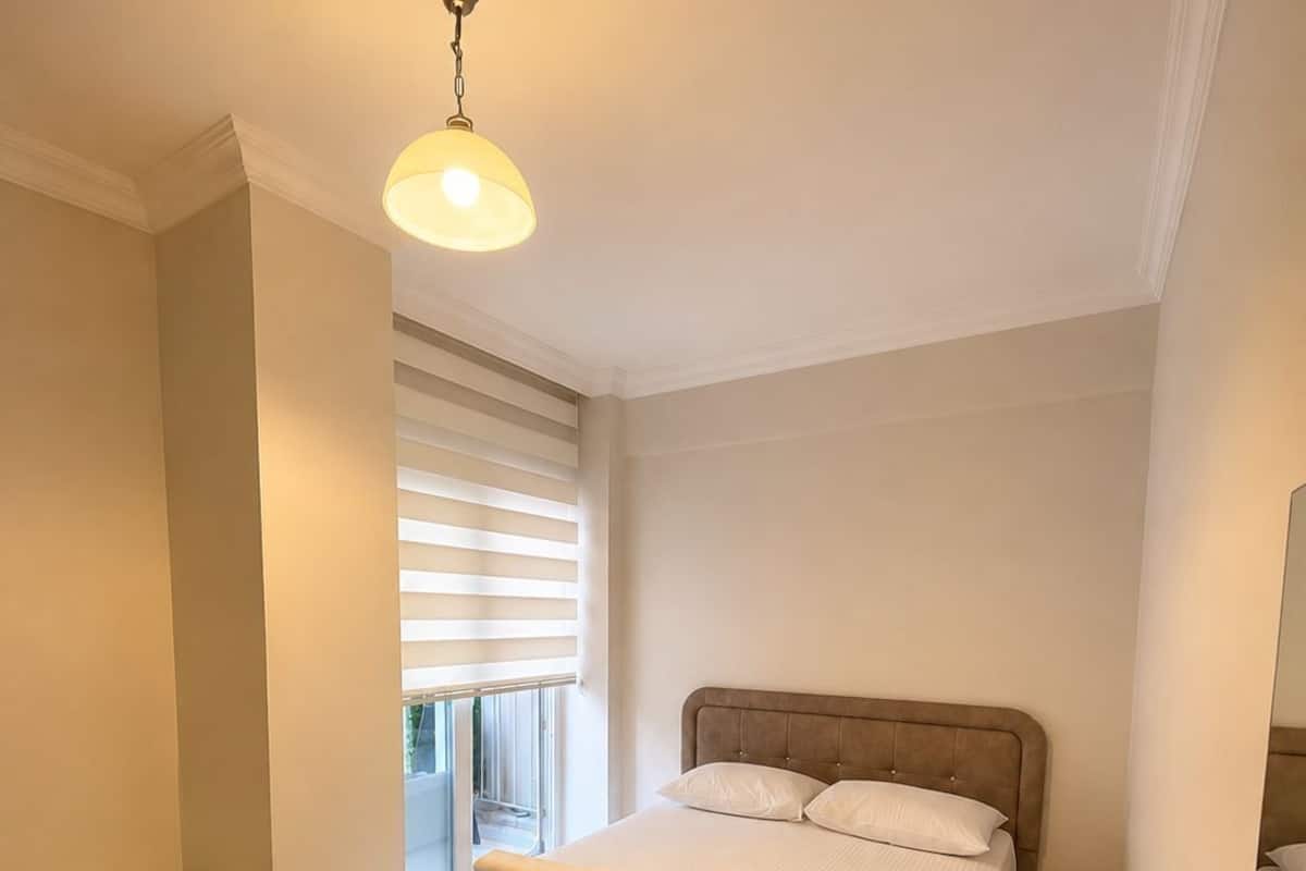 A bedroom with a bed, bedside table, and a hanging light fixture.