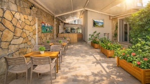 An outdoor dining area with stone walls, wooden tables, and chairs, and potted plants. - STAR APART OTEL MARMARİS  (Marmaris)