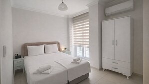 A bedroom with a bed, bedside table, nightstand, wardrobe, and a window with blinds. - STAR APART OTEL MARMARİS  (Marmaris)