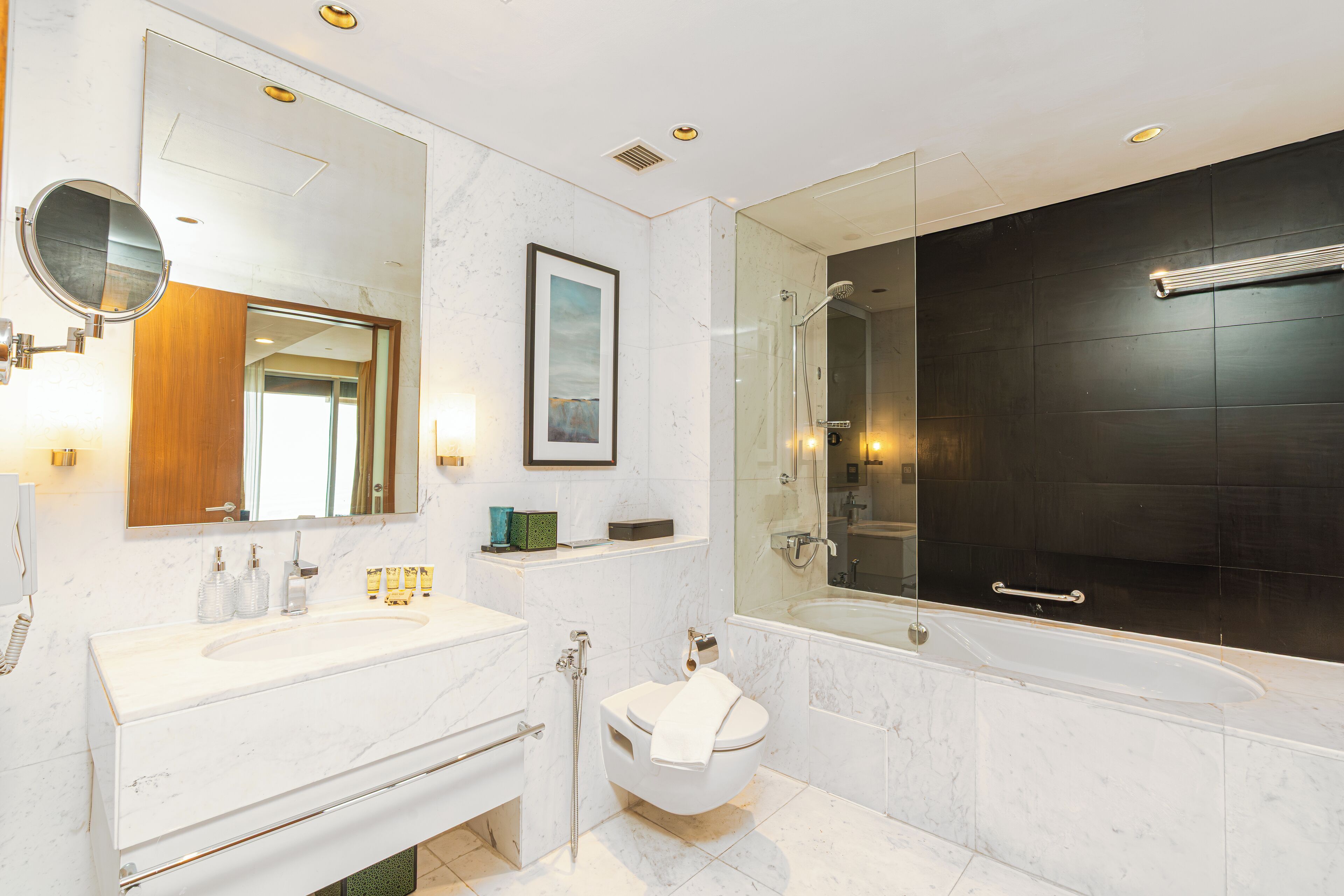 Une salle de bain moderne avec un grand miroir, un lavabo, des toilettes et une baignoire.