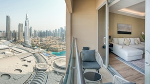 A balcony with a city view, a white sofa, and a glass door leading to a living area. - PVH - 1BR - Emaar Fashion Avenue (Dubai)