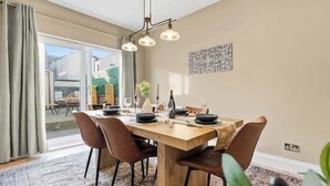 Un comedor con una mesa de madera, sillas marrones y un tapete estampado.