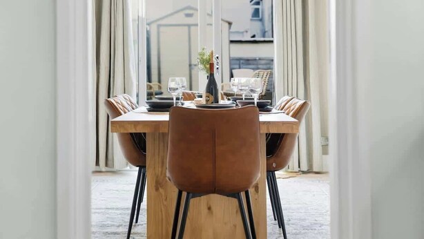 Un comedor con una mesa de madera, sillas y una araña.