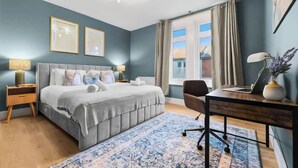 Un dormitorio con cama, escritorio, silla y ventana con cortinas.