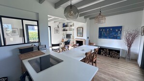 A modern kitchen with a central island, wooden flooring, and a dining area with chairs. - In a haven of peace, charming house, 5 minutes from white sandy beaches (Plounéour-Brignogan-plages)