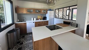 A modern kitchen with wooden cabinets, a white countertop, a black backsplash, and a hanging pendant light. - In a haven of peace, charming house, 5 minutes from white sandy beaches (Plounéour-Brignogan-plages)