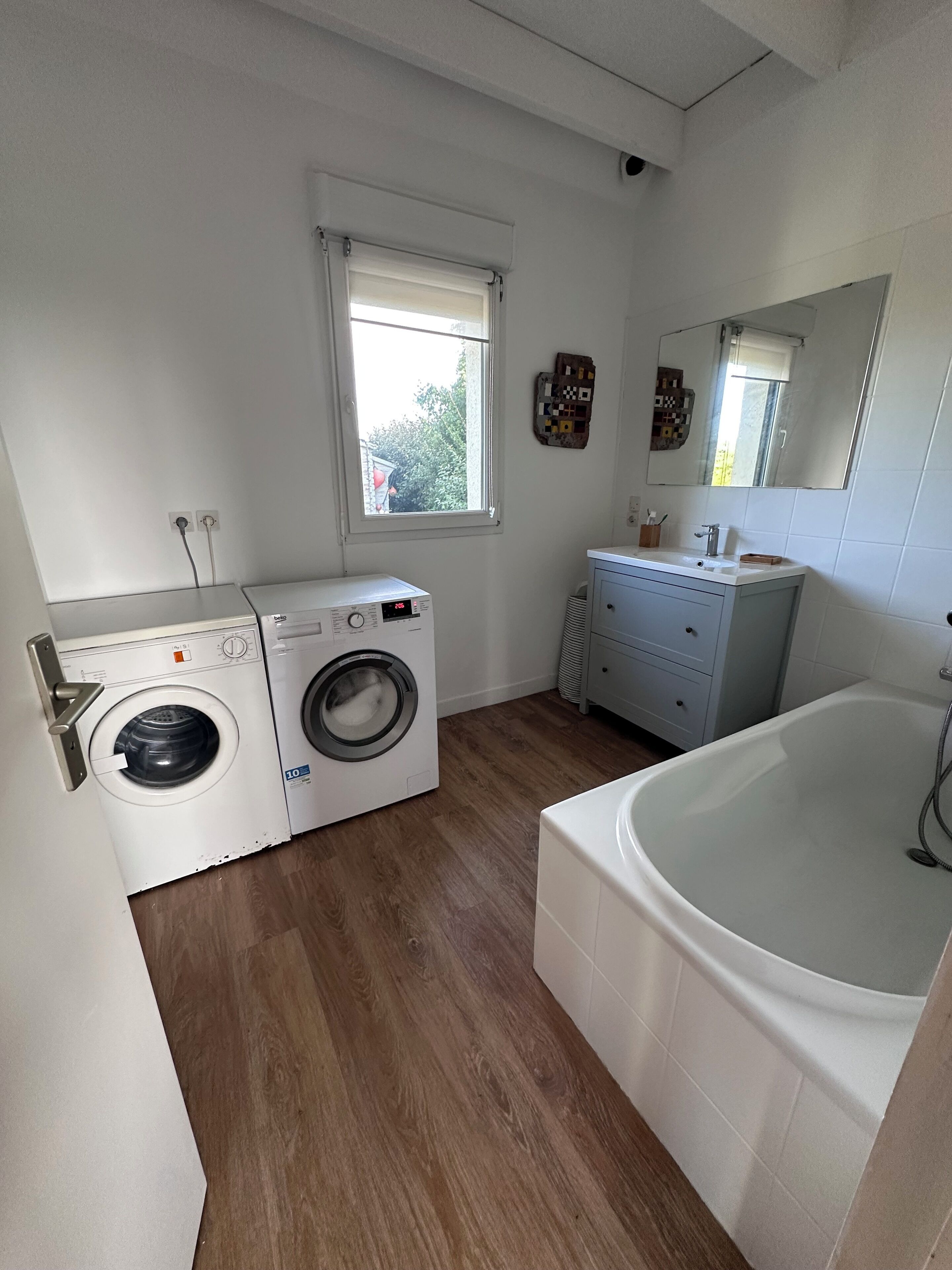 A laundry room with a washing machine, dryer, and a bathtub.