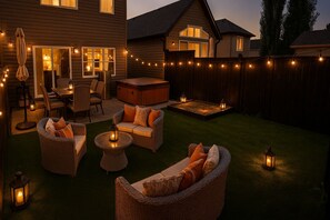 Un jardin avec des meubles d’extérieur, des guirlandes lumineuses et un foyer.