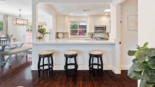 A modern kitchen with white cabinets, a large island with stools, and a view to the outside. - Charming Coastal Retreat in the Heart of OB! Close to the Beach and Seaworld! (San Diego)