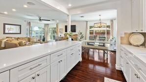 A spacious kitchen with a large island, white cabinetry, and a dining area with a table and chairs. - Charming Coastal Retreat in the Heart of OB! Close to the Beach and Seaworld! (San Diego)