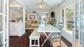 A spacious kitchen with a dining area, large windows, and a ceiling fan. - Charming Coastal Retreat in the Heart of OB! Close to the Beach and Seaworld! (San Diego)