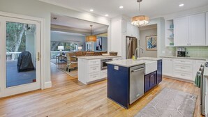 A modern kitchen with white cabinets, a central island, and a built-in dishwasher.