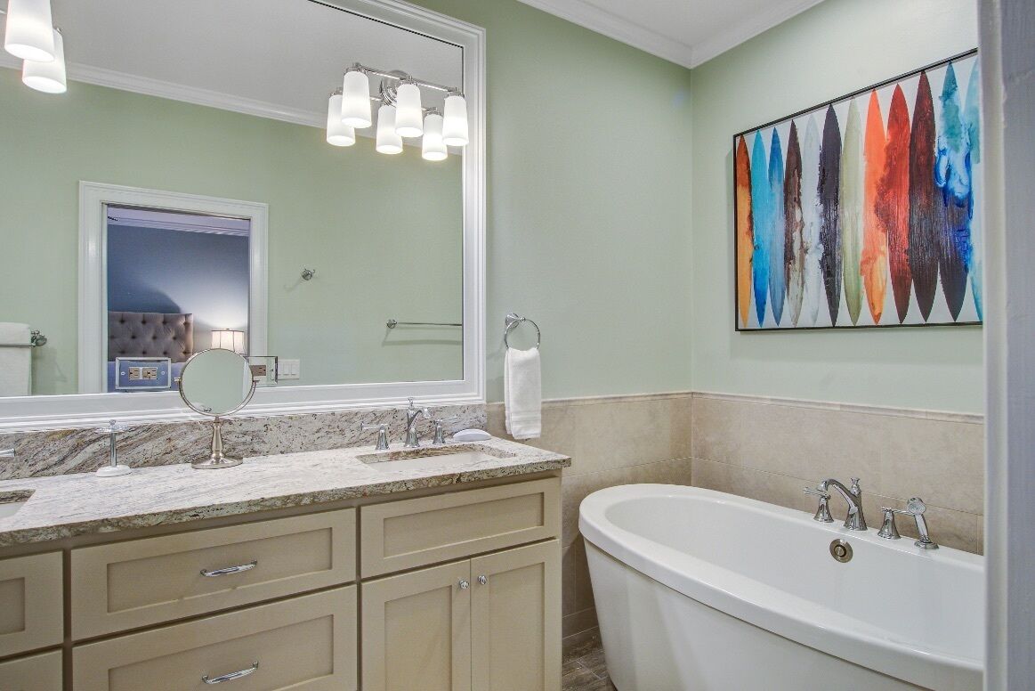 Une salle de bain avec une baignoire îlot, un meuble-lavabo double avec un miroir et un grand tableau abstrait accroché au mur.