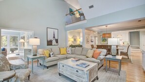 A spacious living room with a large sectional sofa, a coffee table, and a dining area with a chandelier.