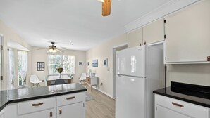 A modern kitchen with white cabinetry, a black countertop, and a built-in refrigerator. - The Captains Deck, Steps to Beach, Family Friendly (Folly Beach)