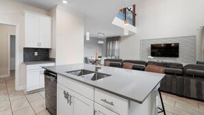 A modern kitchen with white cabinets, a central island with a sink, and pendant lighting.