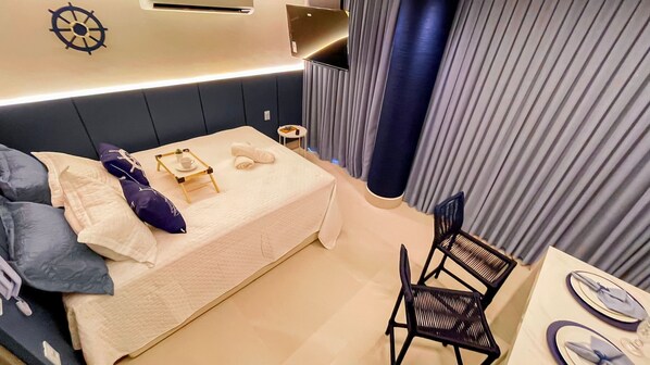 A neatly made bed with pillows and a small bedside table with a cup and saucer. - Setai Aquamaris Garden - By Almare (João Pessoa)