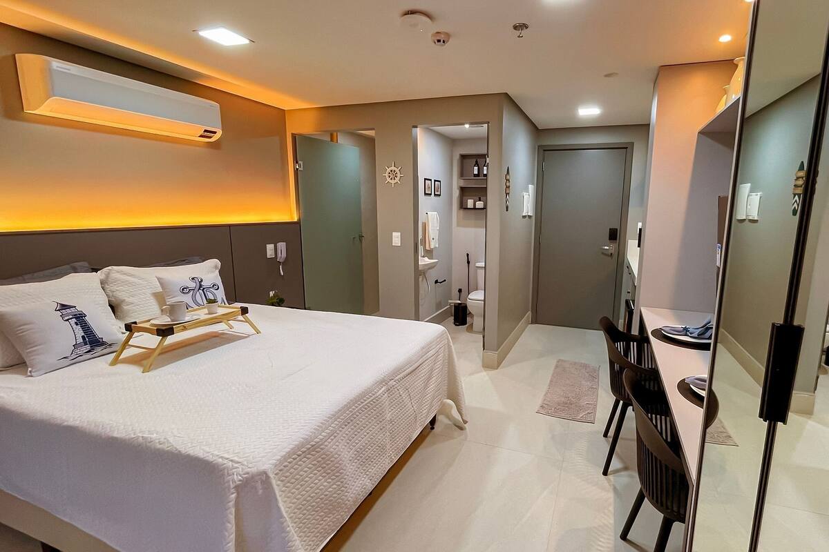 Une chambre d’hôtel avec un lit, une table de chevet, un miroir et une vue sur la salle de bain.