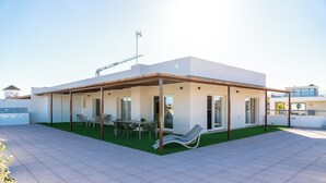 A modern house with a covered patio, a dining area, and a lounge chair. - Luxury Apartment in La Zenia (Orihuela)
