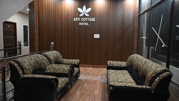 Zona de recepción de hotel con pared de madera, un logotipo y dos sofás.