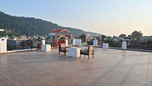 Una terraza en la azotea con zona de estar, una estructura roja y vistas a un paisaje montañoso.