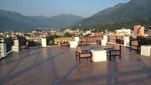 Terraza en la azotea con mobiliario y vistas a la ciudad y montañas.