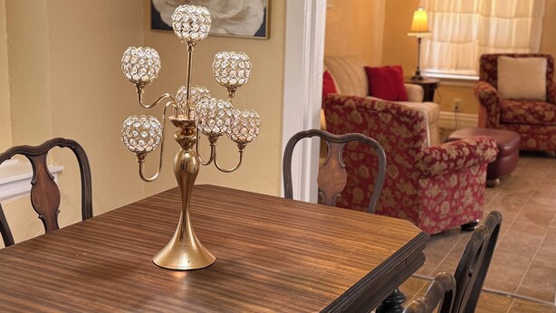 A dining table with a decorative candelabra in a room with floral-patterned furniture and a painting on the wall. - Hidden Gem: Cozy, please read full description (Cleveland)