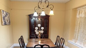 A dining room with a wooden table, six chairs, a chandelier, a patterned rug, and a large cabinet. - Hidden Gem: Cozy, please read full description (Cleveland)