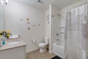A bathroom with a sink, toilet, and bathtub. There are decorative stickers on the wall and a shower curtain with a geometric pattern. - 1Bd1Ba Downtown Suite w/ KING Bed and FREE Garage Parking! (Indianapolis)
