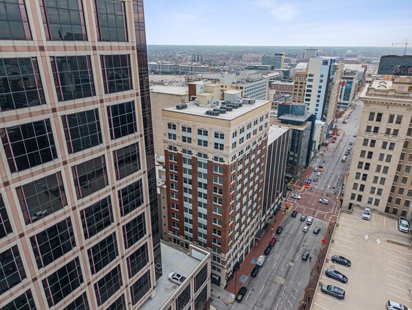 A high-rise building with multiple floors, large windows, and a parking lot with several cars. - 1Bd1Ba Downtown Suite w/ KING Bed and FREE Garage Parking! (Indianapolis)