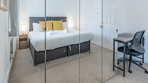 A modern bedroom with a bed, bedside table, and a desk with a chair. - Pass the Keys | Cosy home | Basildon | Ideal for contractors (Basildon)
