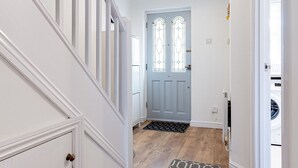 A hallway with a wooden floor, a white door with stained glass windows, and a black and white rug. - Pass the Keys | Cosy home | Basildon | Ideal for contractors (Basildon)