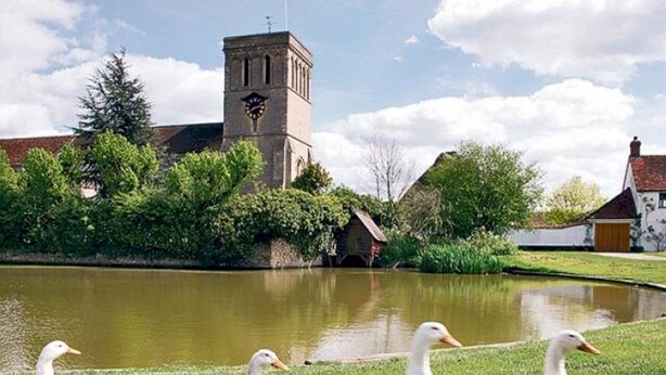 A pond with ducks, a clock tower, and a building with a red roof. - Pass the Keys |Modern Penthouse Style Apartment in Haddenham (Aylesbury)