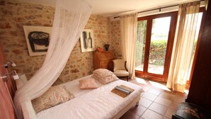 Une chambre à coucher comprenant un lit, une chaise, une armoire en bois et une fenêtre avec des rideaux.