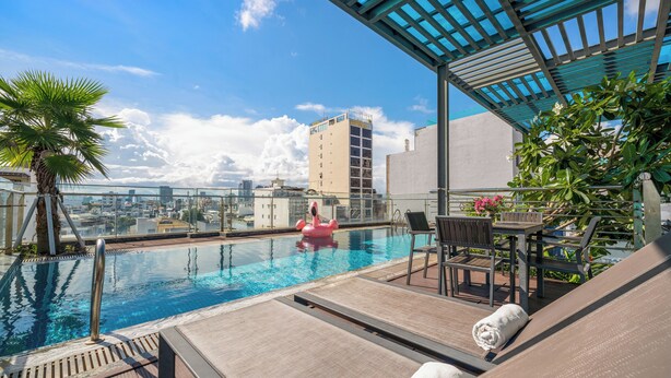 A rooftop pool with lounge chairs, a table, and a pink flamingo float. - Happy House Hotel & Apartment (Da Nang)