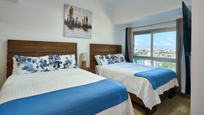 Ein Hotelzimmer mit zwei Betten, Blick auf die Stadt und einem Gemälde an der Wand.
