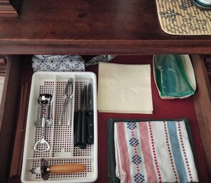 A drawer with a white tray containing various kitchen utensils, a knife, a wooden-handled tool, and a folded cloth with a striped pattern. - Intra Muros. 2 minutes from the beach. (Saint-Malo)