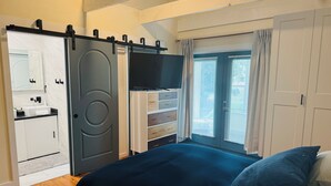 A bedroom with a bed, a TV, a sliding door, a dresser, and a window with curtains. - The Quiet House on Main Street minutes from Everywhere (Shrewsbury)