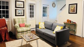 A living room with a sofa, armchair, and coffee table, featuring framed pictures on the walls. - The Quiet House on Main Street minutes from Everywhere (Shrewsbury)