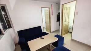 A room with a dark blue sofa, a small table, and matching ottomans. There are two doors leading to other areas. - Cozy 2nd Floor Apartment in Heart of Cartagena (Cartagena)