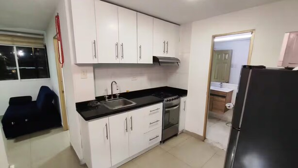 A kitchen with white cabinets, a black countertop, stainless steel appliances, and a tiled floor. - Cozy 2nd Floor Apartment in Heart of Cartagena (Cartagena)