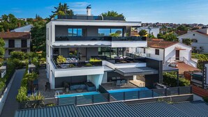 A modern two-story house with a rooftop pool, a balcony, and a view of the surrounding neighborhood. - Holiday apartment Luxurious flat with a beautiful terrace overlooking the sea (Njivice)