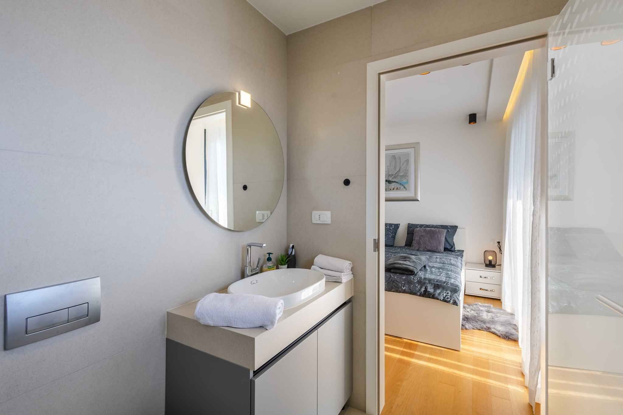 A modern bathroom with a round mirror, a sink, and a towel.