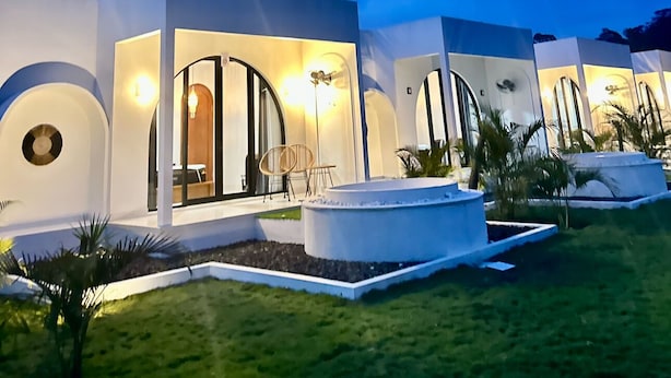 A modern villa with multiple entryways, each with a glass door and a small seating area. - Hideout Kintamani and Hot Spring (Kintamani)