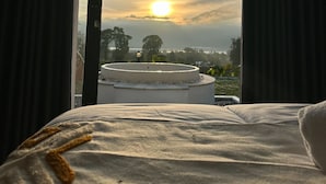 A bedroom with a large window, a bed, and a circular outdoor feature. - Hideout Kintamani and Hot Spring (Kintamani)