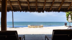 A beachside lounge with a thatched roof, a stone fire pit, and lounge chairs facing the ocean. - Pelicano. Beachfront 2 floor condo in Bucerias (Bucerías)