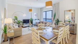 A modern living room with a sofa, TV, and dining area with chairs and a table.