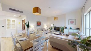 A modern living room with a dining area, a sofa, a TV, and a cabinet.